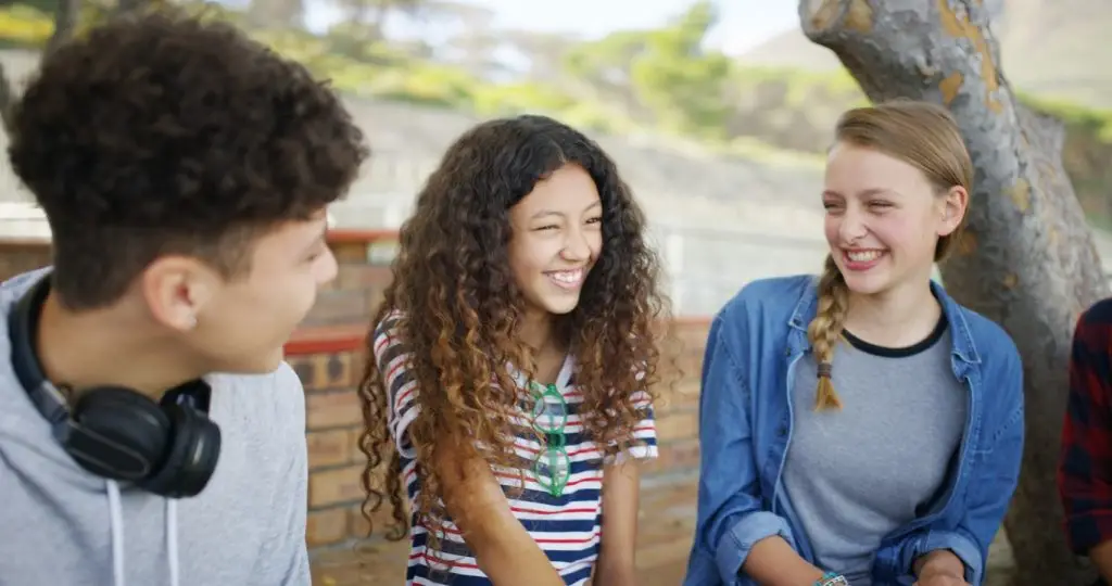 High school, break and students outdoor for talking, conversation and chat together on campus. Academy, teenagers and friends laughing for funny story, gossip and discussion at recess for education